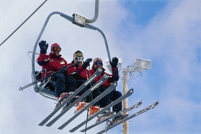 Skiers smiling and waving on the ski lift