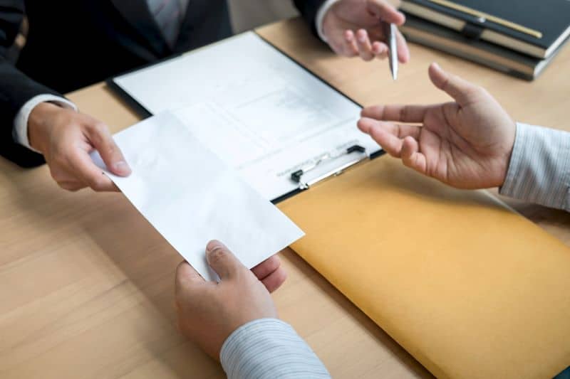 lawyer giving their client an envelope with their settlement