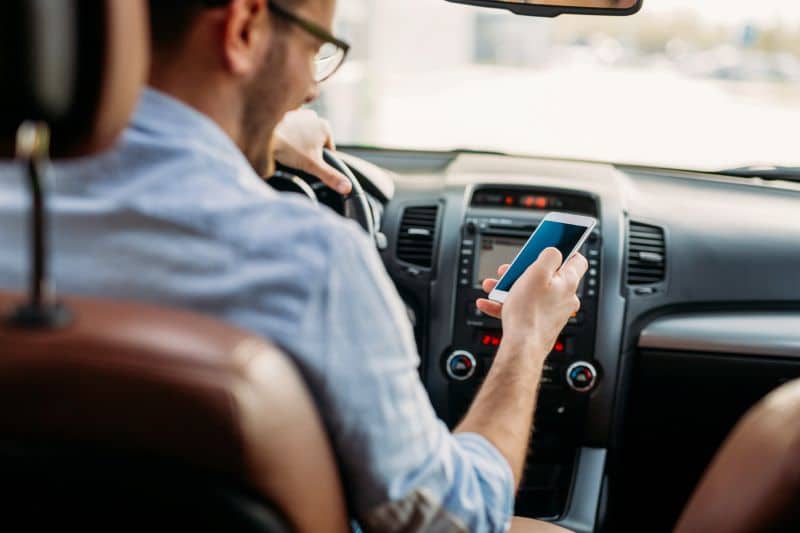 man looking at his mobile phone while driving