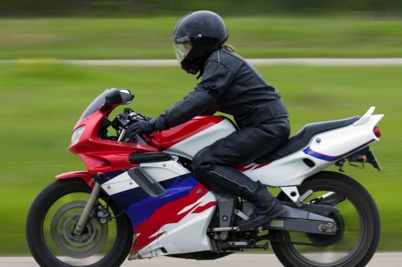 woman riding a motorcycle safely with a helmet
